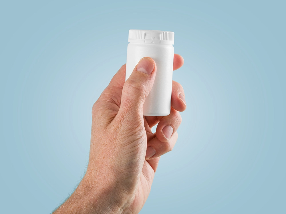 Nolato Pharma Packaging hand håller en burk